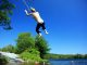 Teen boy jumping off rope swing over water