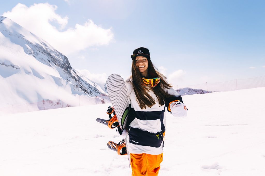 Girl holding a snowboard on the snow