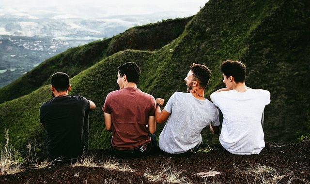Four guys friends sitting on mountain top