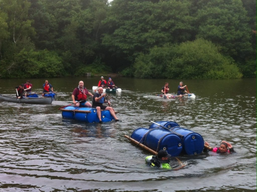 Teams raft racing with one team falling in the water