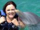 Dolphin kissing a woman swimming with dolphins