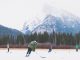 Playing ice hockey outdoors on a lake with the mountains in the background