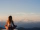 Woman sitting meditating on the top of a mountain